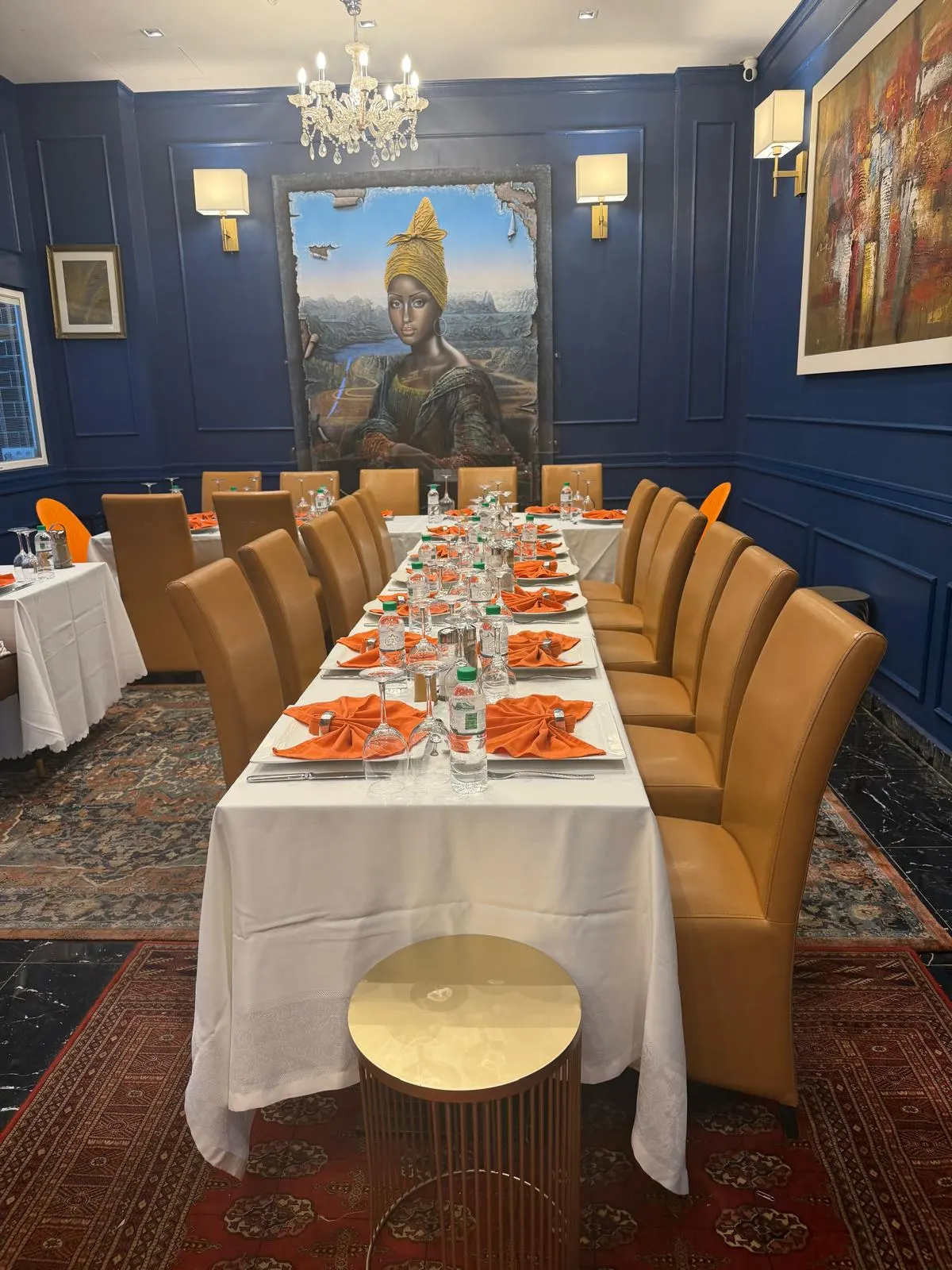 Longue table dressée pour un repas de groupe, serviettes orange pliées et chaises ocre alignées
